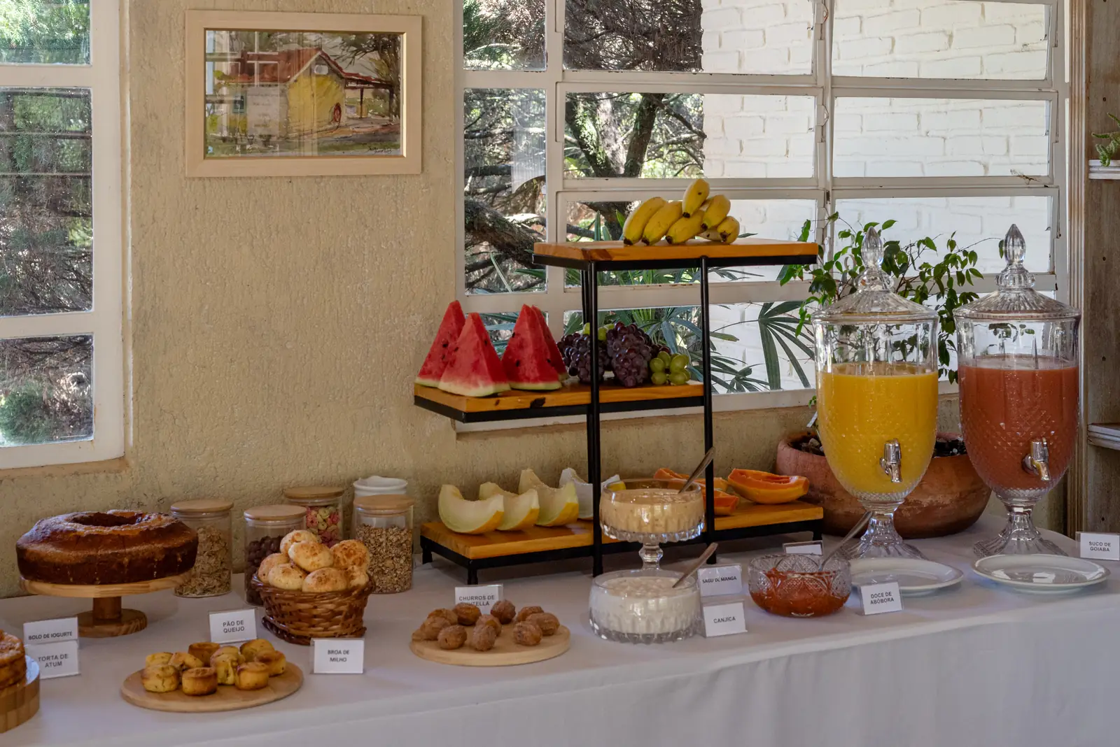 Bolos, frutas e sucos lado a lado sob as janelas