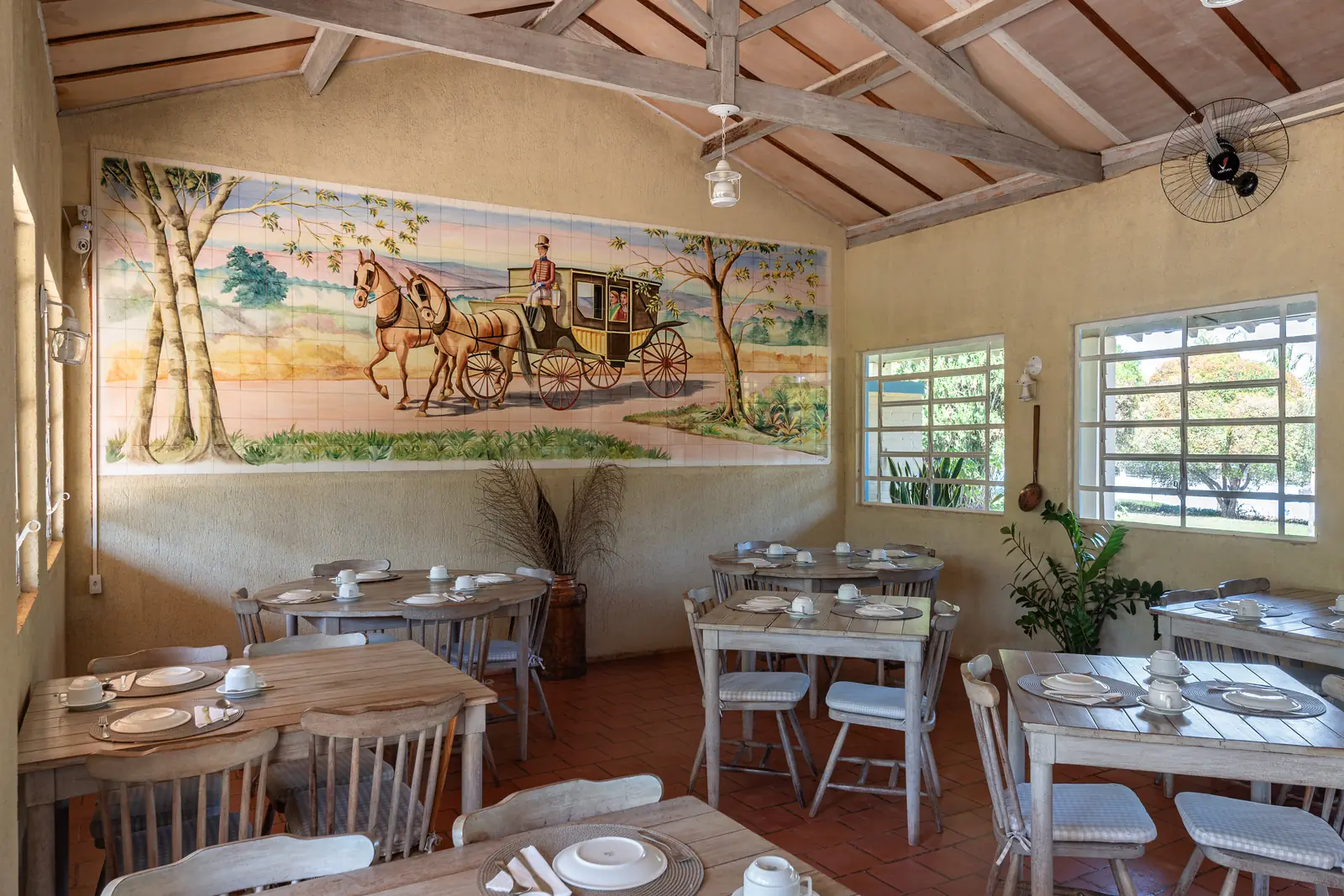 Painel pintado e mesas postas no salão do café